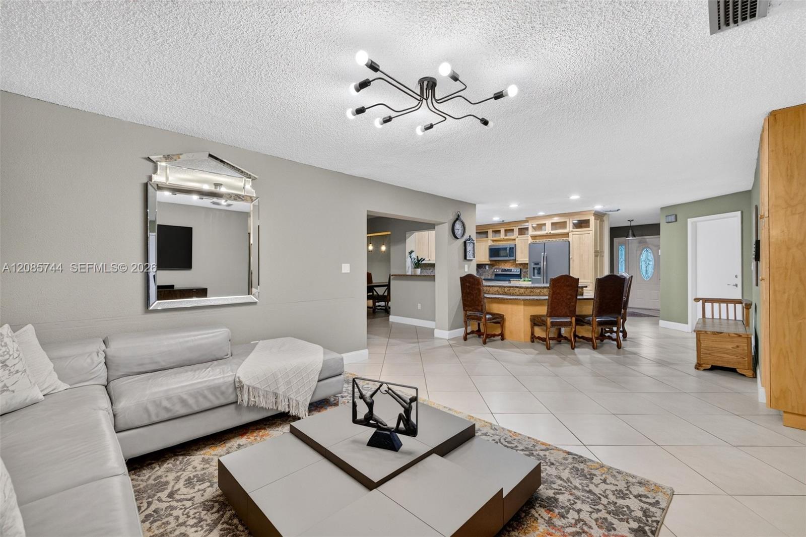 Bright family room / open concept great room - tile on diagonal, two bedrooms split to the right, primary beyond the kitchen to the left. Great floorplan