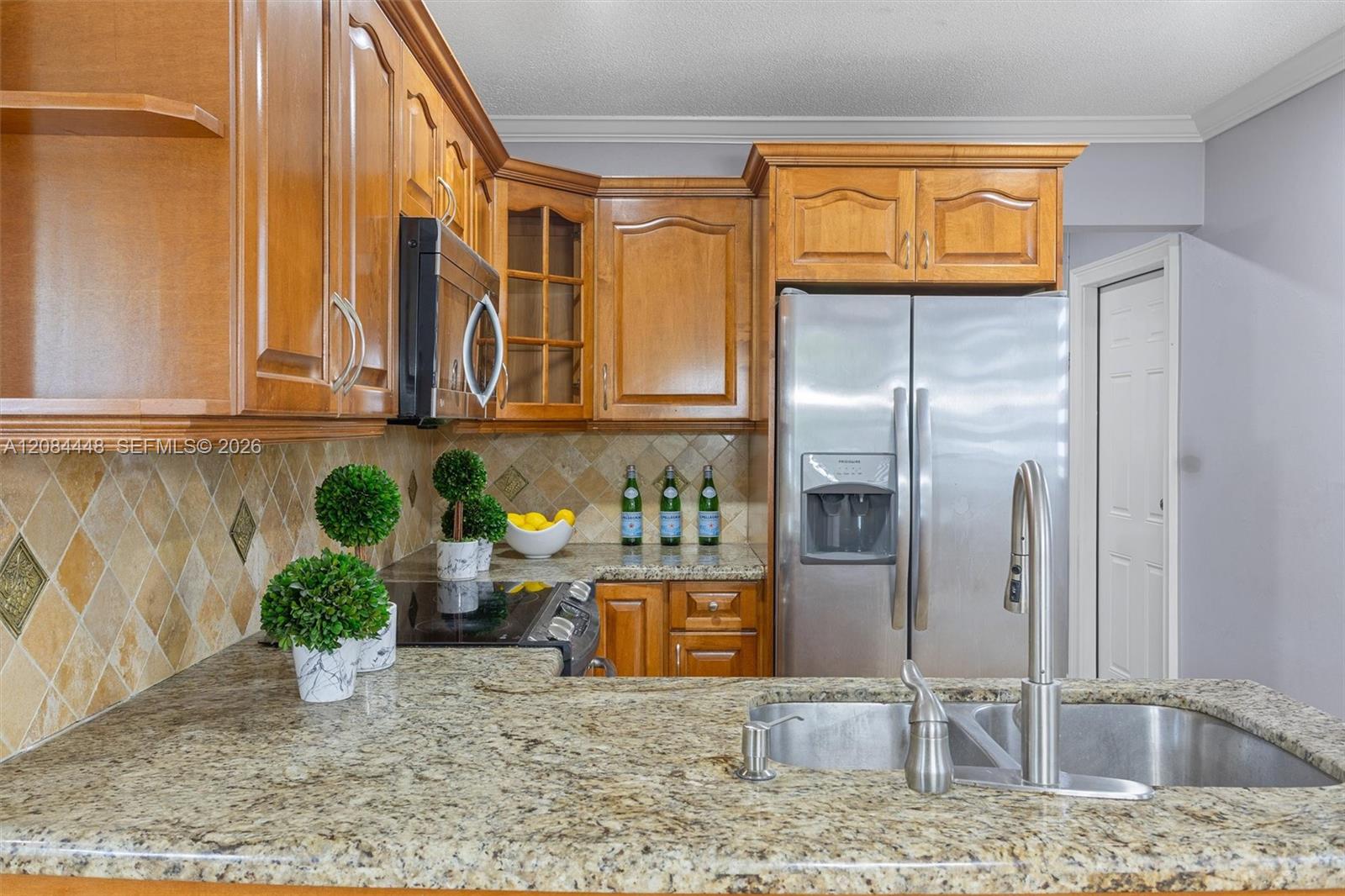 This beautifully appointed kitchen combines warmth and functionality with its rich wood cabinetry, granite countertops, and stainless-steel appliances
