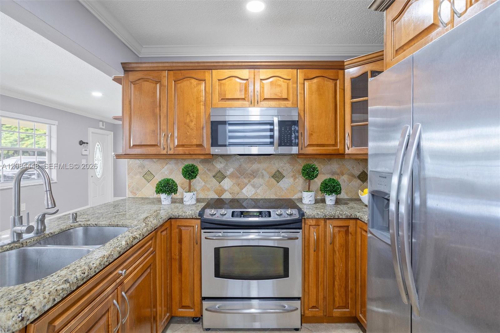 This beautifully appointed kitchen combines warmth and functionality with its rich wood cabinetry, granite countertops, and stainless-steel appliances