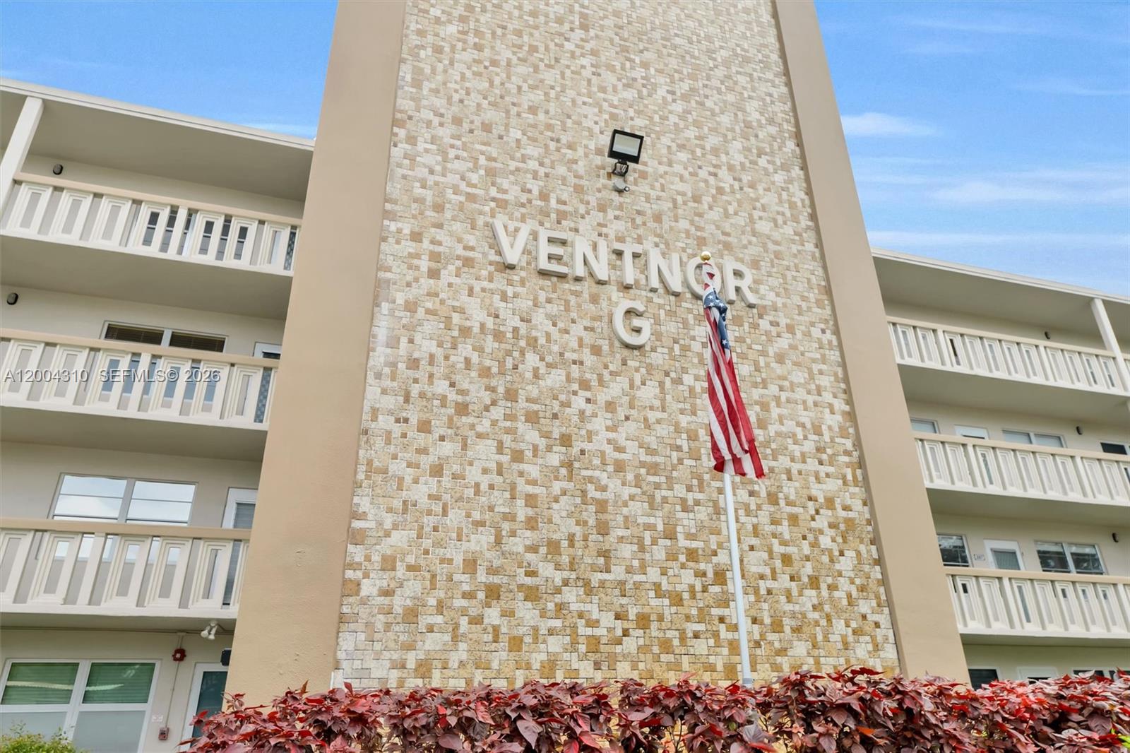 Close-up "VENTNOR G" signage tower with American flag and red foliage