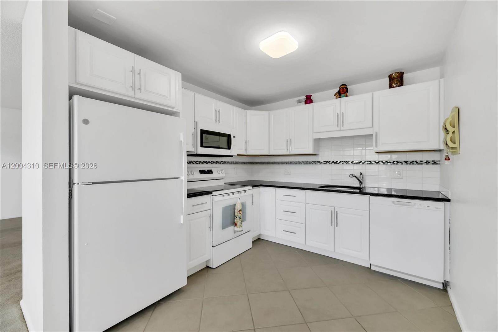 Full view, white shaker cabinets, dark granite counters, tile backsplash with mosaic accent strip, & all appliances