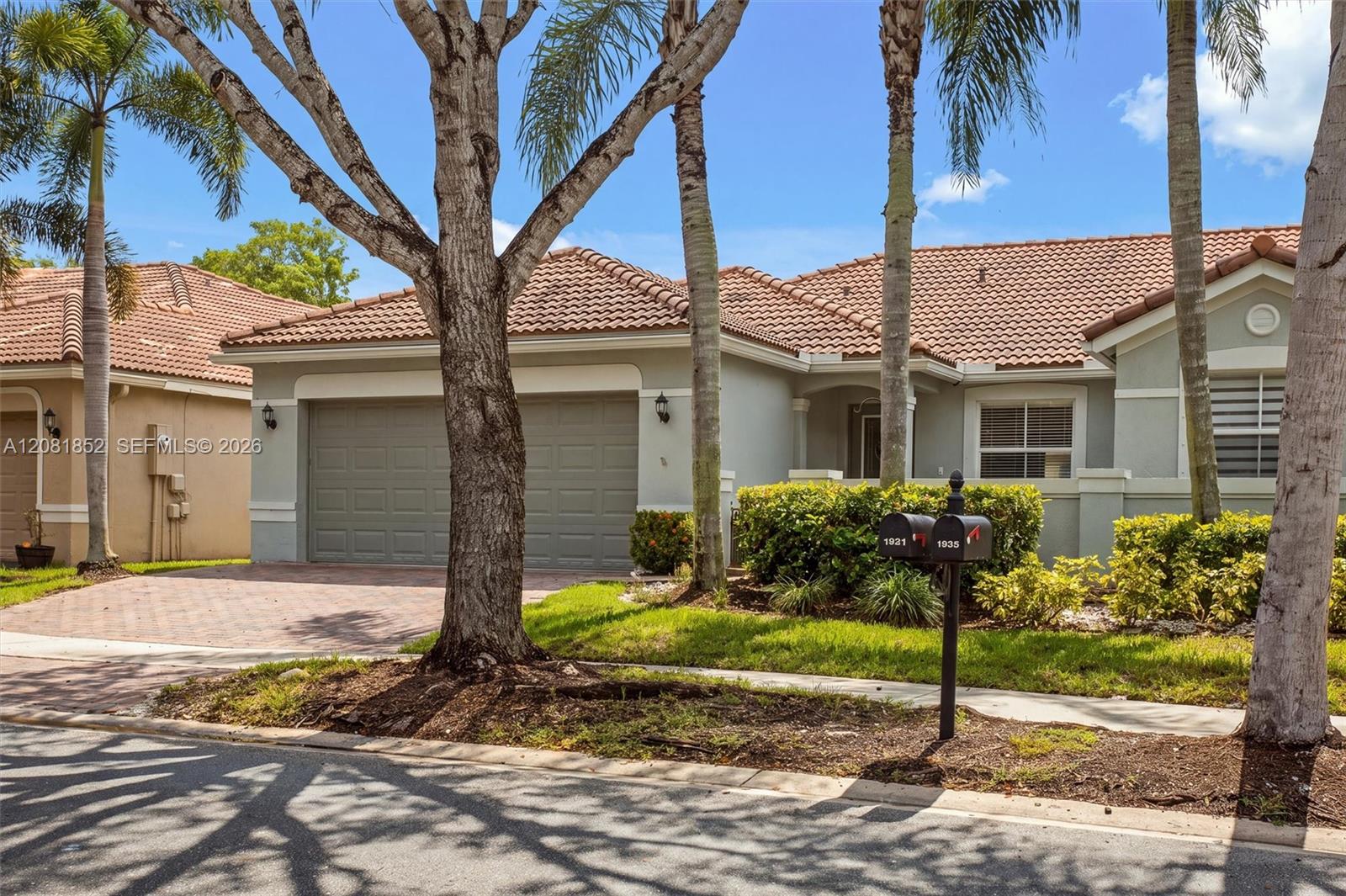 Manicured landscaping and swaying palm trees frame this home's inviting curb appeal.