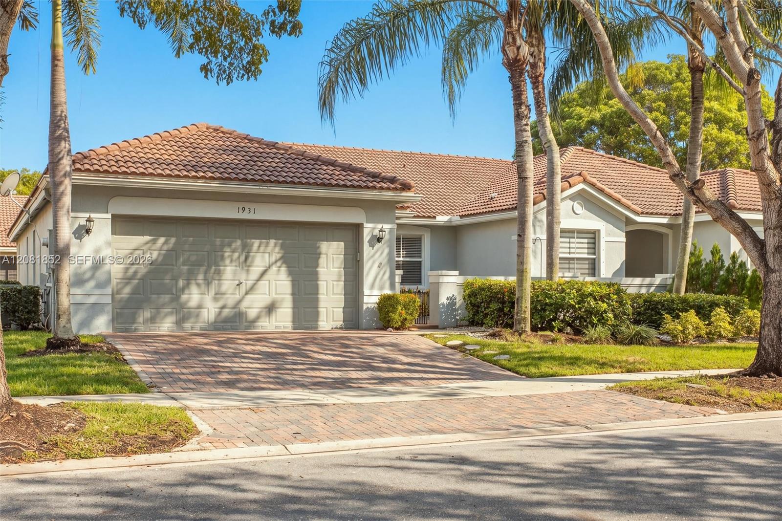Elegant entry with two-car garage set amid lush tropical landscaping.