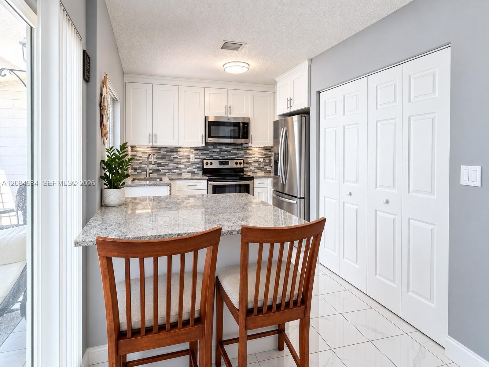 kitchen area with white cabinetry, stainless steel appliances, tile flooring, and a breakfast bar.