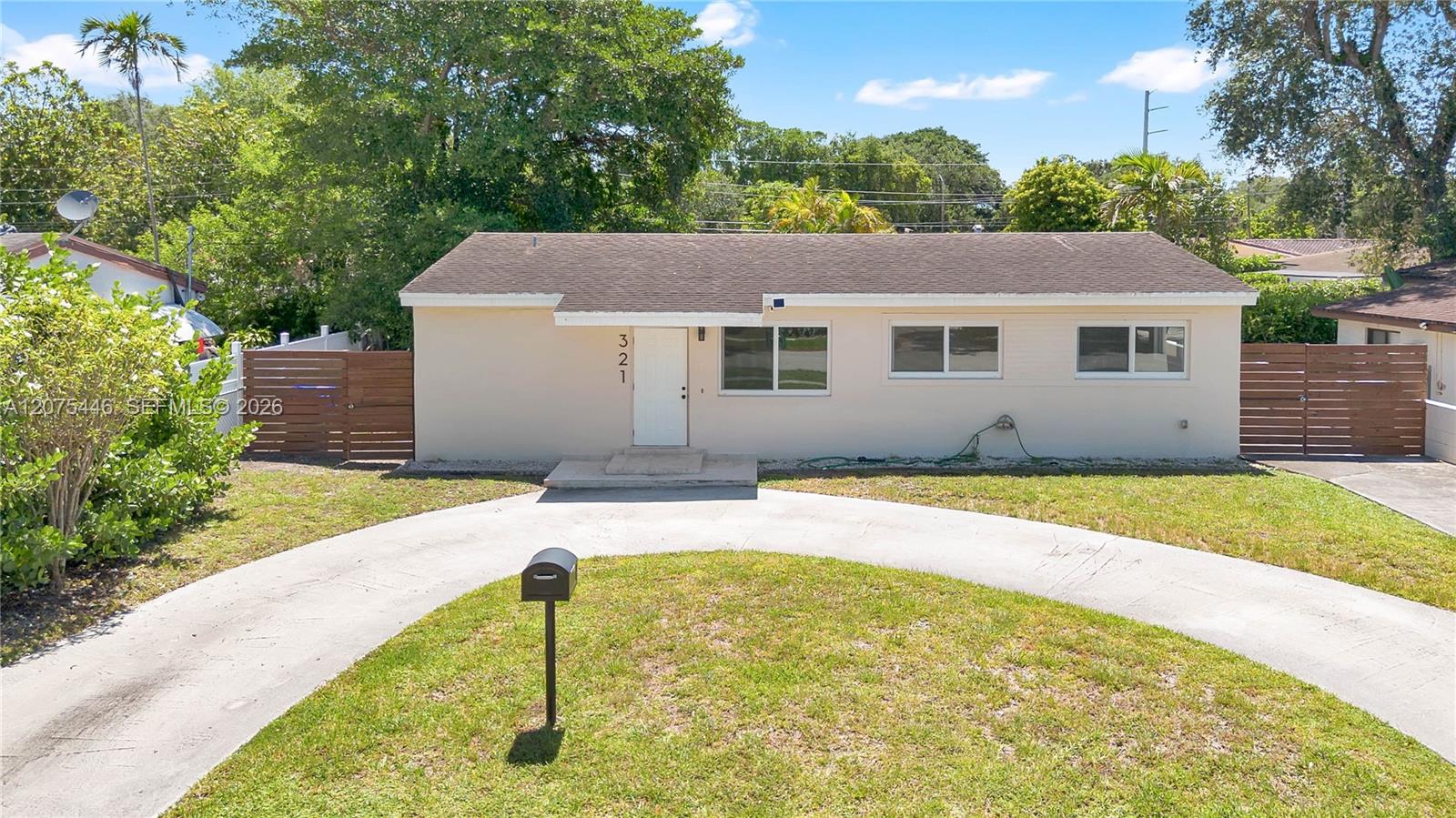 Well-maintained home featuring a circular driveway, privacy fencing, and spacious front yard.