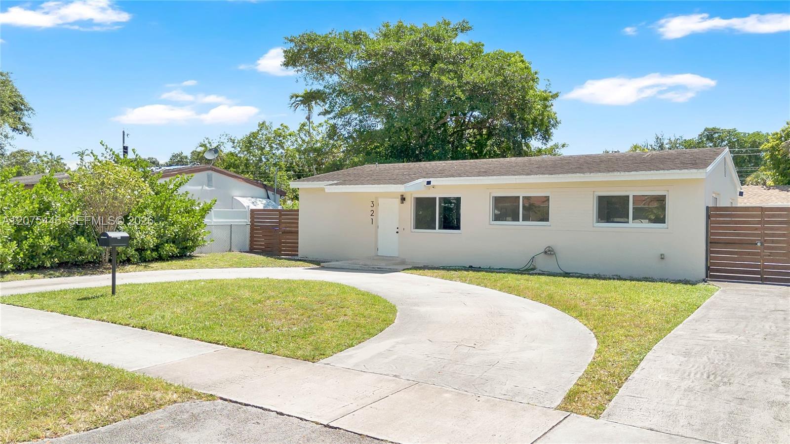 Modern home with a circular driveway, fenced yard, and inviting curb appeal.