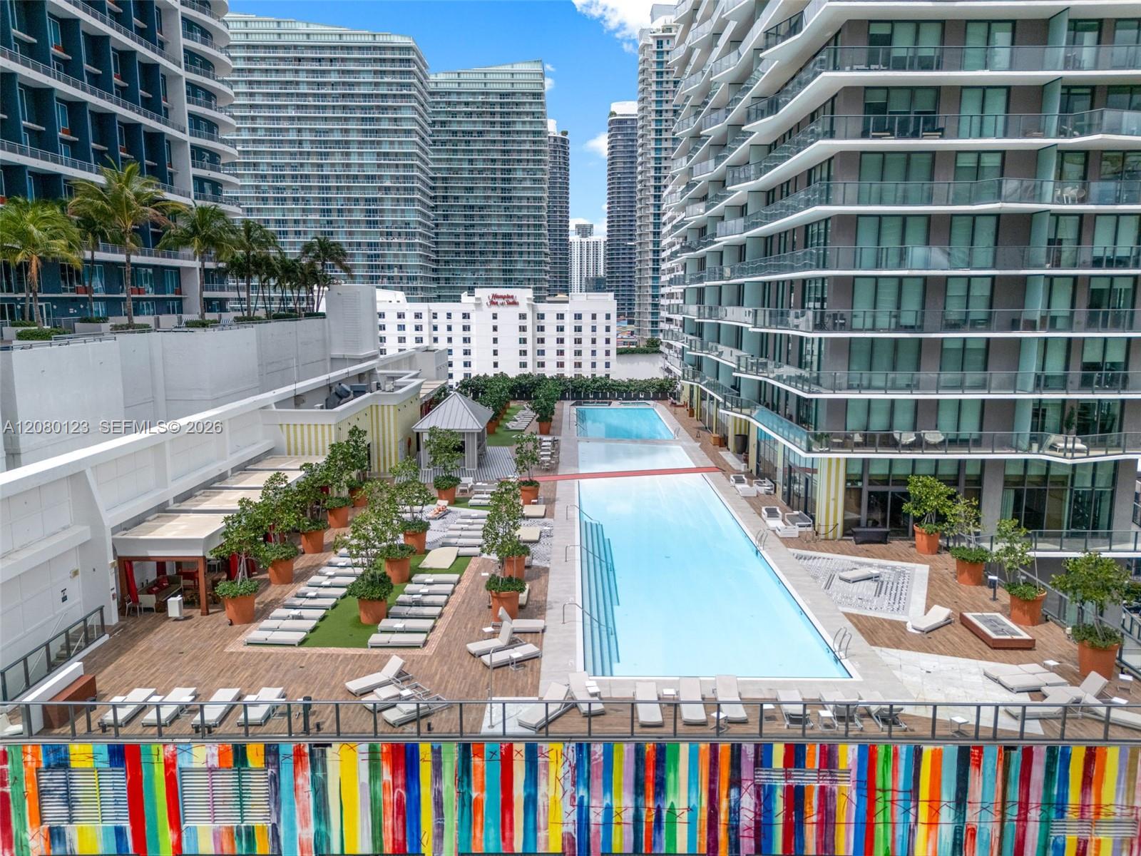 Resort-style pool deck with cabanas, sunbeds, and tropical landscaping at SLS Brickell Dua.