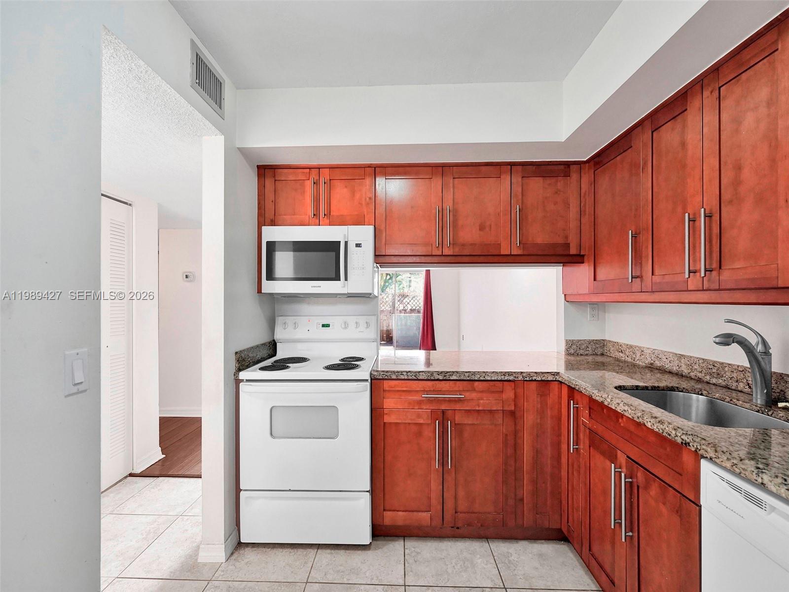 Updated kitchen boasts granite counteers and wood cabinets.