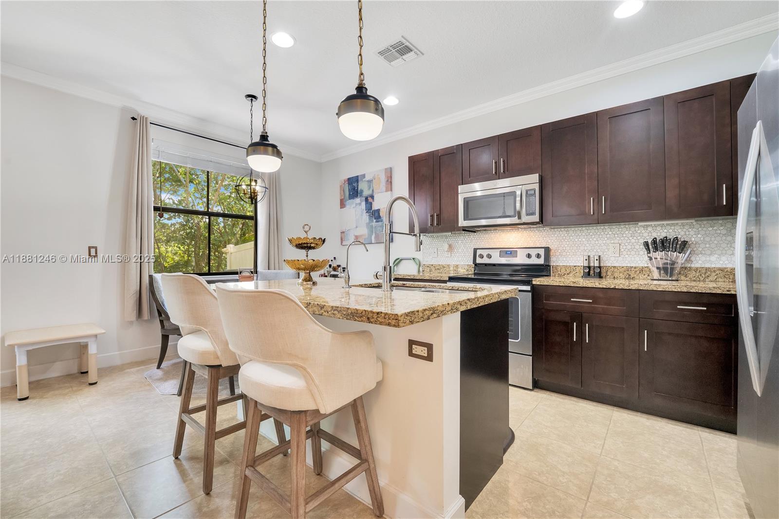 Modern kitchen with granite counters, stainless steel appliances, and rich wood cabinetry. Bright breakfast nook by the window offers a cozy dining space with natural light.